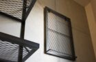 シューズクロークのコンクリート壁面に施工した黒皮鉄のハンギングメッシュフレーム全体