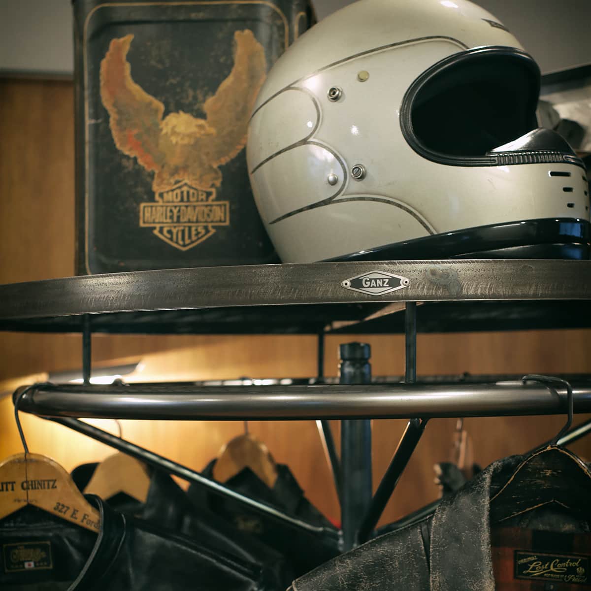 店舗什器のサークルハンガーラックとメッシュシェルフ。ライダースジャケットやヴィンテージヘルメットが映えるインダストリアルなディスプレイ。One Photo -077-