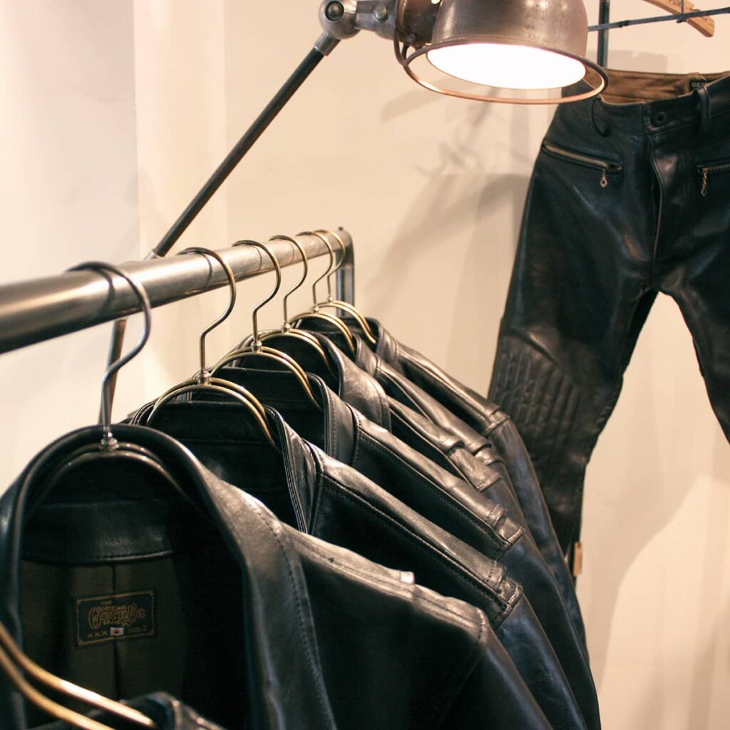GANZ定番の黒皮鉄製ハンガーラック(店舗什器)とレザージャケット・レザーパンツのディスプレイ。